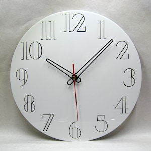 K&ouml;nnte beinhalten: Eine wei&szlig;e runde Uhr mit schwarzen r&ouml;mischen Ziffern als Stundenmarkierungen und schwarzen Zeigern. Der Minutenzeiger ist rot.