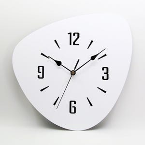 May include: White, modern wall clock with black hands and numbers. The clock face is shaped like a teardrop and has a minimalist design.
