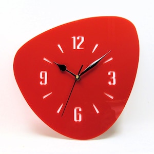 May include: A red, retro-style wall clock with a unique, asymmetrical shape. The clock face features white numerals at 12, 3, 6, and 9 o'clock, with black hands. The clock's design is a vibrant, eye-catching accent piece.