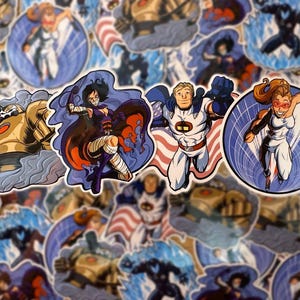 May include: A collection of colorful superhero stickers. The stickers feature various characters in action poses, including a robot, a figure in a cape, and a woman in a white suit. The stickers have a comic book style with bold lines and vibrant colors.