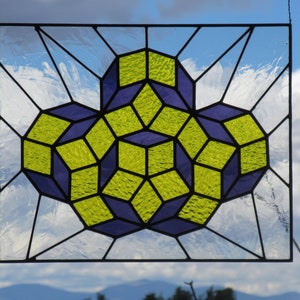 May include: A rectangular stained glass panel featuring a geometric pattern of interlocking cubes in lime green and deep purple. The design is composed of textured glass pieces held together by dark metal lead lines, creating a repeating 3D effect.