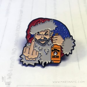 May include: A red and white Santa Claus pin with a beard and a bottle of orange liquor in his hand. He is giving the middle finger. The pin is on a white background with a blue glitter background.