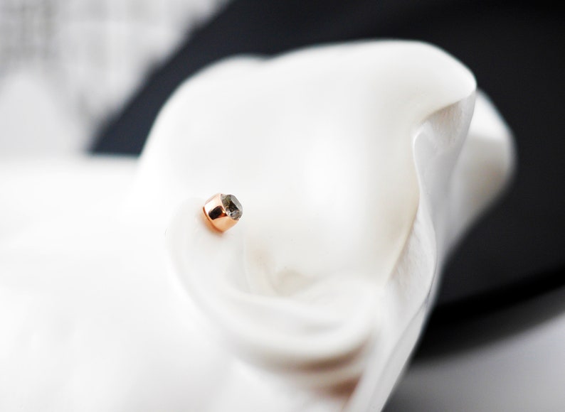 K&ouml;nnte beinhalten: Ein kleiner, runder Ohrstecker aus Ros&eacute;gold mit einem schwarzen Diamanten.
