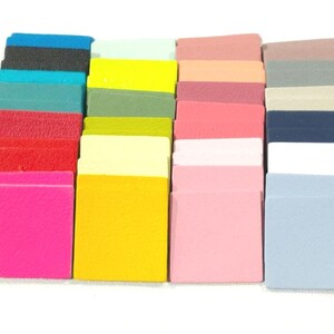 May include: A collection of 24 small, square fabric swatches in various colors, including pink, yellow, blue, green, and red. The swatches are arranged in rows and columns.