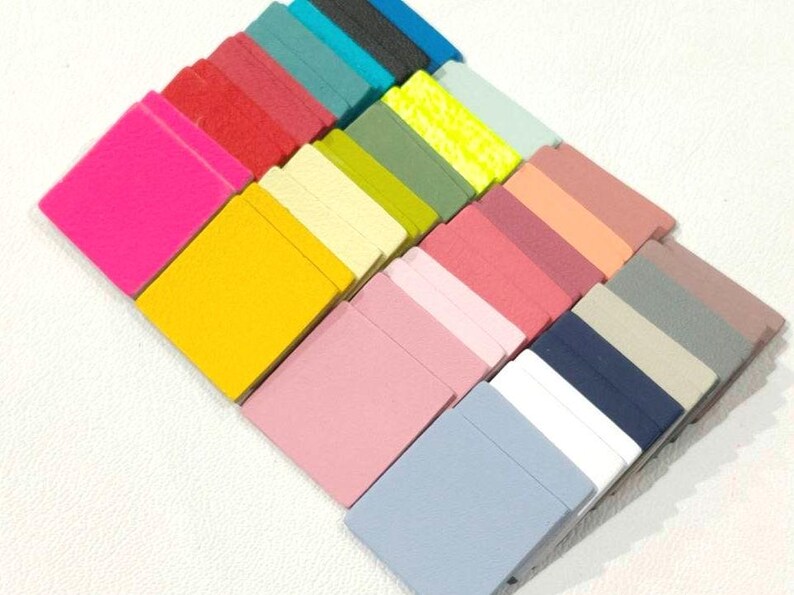 May include: A collection of 20 small, square fabric swatches in various colors, including pink, yellow, blue, green, and gray. The swatches are arranged in a staggered pattern, with the brightest colors at the top and the darker colors at the bottom.