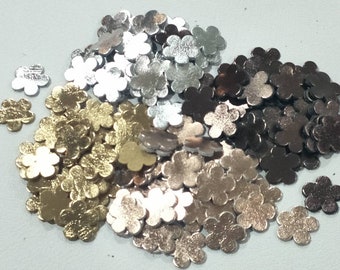 May include: A pile of metallic flower-shaped confetti in gold, silver, and bronze colors.