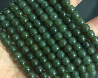 Pode incluir: Um fio de contas de jade verde escuro. As contas são redondas e lisas, e são enfiadas em um fio transparente.