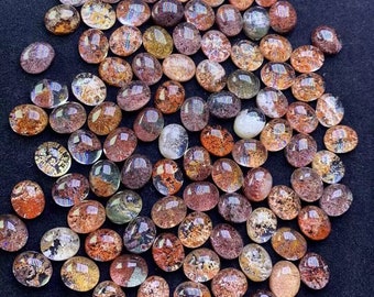 May include: A collection of oval-shaped, translucent, iridescent gemstones with brown, orange, and white inclusions. The stones have a variety of patterns and colors, and they are arranged in a random pattern.