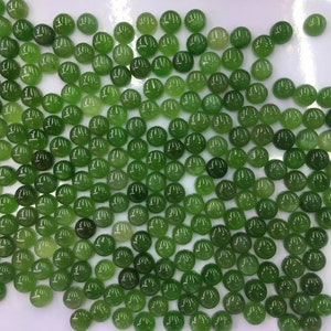 Könnte beinhalten: Eine Sammlung runder, grüner Cabochon-Edelsteine. Die Steine sind glatt und poliert, mit einem leichten Glanz.