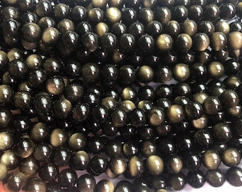 May include: A strand of black and gold gemstone beads. The beads are round and have a smooth, polished finish. The beads are strung on a clear string.