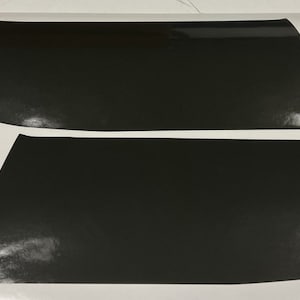 May include: Two black vinyl car window tint sheets with rounded corners and a small circle cutout in each sheet.