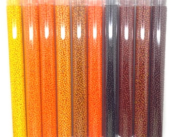 Può includere: Set di dieci perline da seme 11/0 in colori autunnali, tra cui giallo, arancione, marrone e nero. Le perline sono confezionate in tubi trasparenti con etichette che includono la dimensione delle perline, il colore e l'indirizzo del sito web. Le etichette includono anche il prezzo e il peso delle perline.