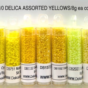 Puede incluir: Siete tubos transparentes llenos de cuentas Delica amarillas surtidas. Los tubos están etiquetados con códigos de producto y "11/0 DELICA ASSORTED YELLOWS/8g ea color". Las cuentas varían en tonos desde amarillo claro hasta chartreuse vibrante.