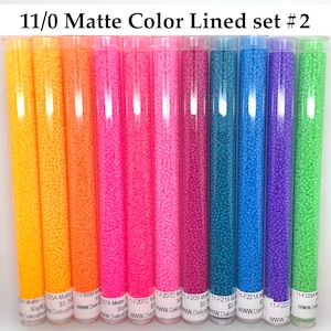 May include: Set of 11/0 size matte color lined seed beads in ten different colors: yellow, orange, pink, hot pink, magenta, teal, blue, purple, and green. The beads are in small clear tubes with labels that include the color number and the word "Delica".