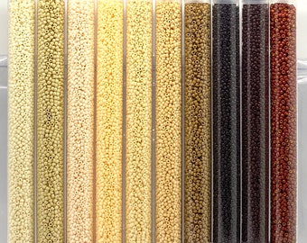 May include: A set of 10 small tubes filled with 11/0 size round seed beads in various shades of tan and brown. The tubes are labeled with the bead size, color number, and price per 30 grams. The set is labeled "11/0 Op Tans n Browns round seed beads set/30g ea".