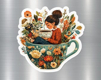 Op de afbeelding: Een sticker met een vrouw in een oranje trui die in een turquoise theekop vol bloemen zit. Ze houdt een kop koffie vast. De theekop is versierd met bloemen. De sticker heeft een witte rand.