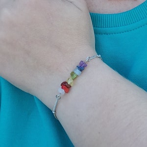 Peut inclure: Un collier et un bracelet en chaîne argent avec des perles de pierres précieuses arc-en-ciel. Le collier a une chaîne délicate et le bracelet a un fermoir simple.