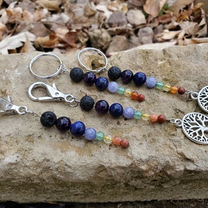 May include: Three silver keychains with a tree of life charm. Each keychain features a beaded strand with black lava rock, amethyst, lapis lazuli, blue aventurine, green aventurine, citrine, and carnelian beads.