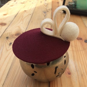 May include: A burgundy felt hat with a white felt bunny ear embellishment.