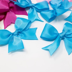 May include: Assortment of colorful satin ribbon bows in various shades of blue, pink, green, and purple. The bows are arranged on a white background.