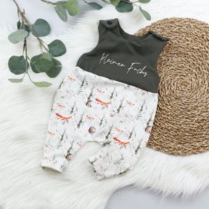 Puede incluir: Un pelele de bebé verde y blanco con estampado de zorro. El pelele tiene una parte superior verde con el texto "Kleiner Fuchs" en blanco.