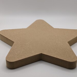 Peut inclure: Une grande étoile en bois brut. L'étoile est en bois brun clair et a une surface lisse.