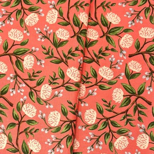 May include: Coral pink fabric with a repeating pattern of white flowers and green leaves.