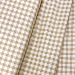May include: Beige and white gingham fabric with a checkered pattern. The fabric is folded in half, showing the pattern on both sides.