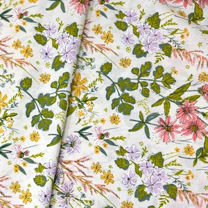 May include: Floral fabric with a cream background. The fabric features a repeating pattern of pink, yellow, and purple flowers, along with green leaves and brown grass-like elements. The design is a mix of detailed and sketched elements.