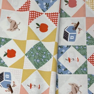 May include: A cotton fabric featuring a patchwork quilt pattern with repeating illustrations of chickens, blue chicken coops, red apples, apple cores, and floral squares in shades of blue, green, yellow, and red gingham on a white background.