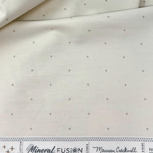 May include: White fabric with a subtle pattern of small brown crosses. The fabric has a label that reads "Mineral Fusion" and "Maureen Cracknell".