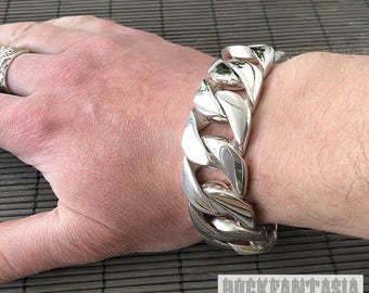 May include: A silver chain bracelet with large, chunky links. The bracelet is worn on a person's wrist.