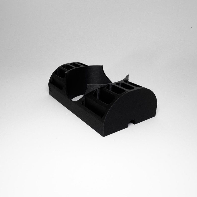 K&ouml;nnte beinhalten: Ein schwarzer, 3D-gedruckter Schreibtisch-Organizer mit mehreren F&auml;chern und einem geschwungenen Design. Der Organizer hat eine rechteckige Basis und abgerundete Enden mit verschiedenen Schlitzen und Abschnitten zur Aufbewahrung von Gegenst&auml;nden.