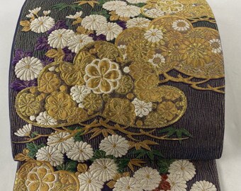 Könnte beinhalten: Ein dunkelblauer Stoff mit einem goldenen und weißen Blumenmuster. Der Stoff ist mit einem strukturierten Design gewebt und zeigt ein sich wiederholendes Muster aus Chrysanthemen und Blättern.