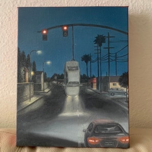 May include: A painting of a street scene at night with a car upside down in the middle of the road. The car is white and has its headlights on. There are streetlights and palm trees in the background. The painting is done in a realistic style.