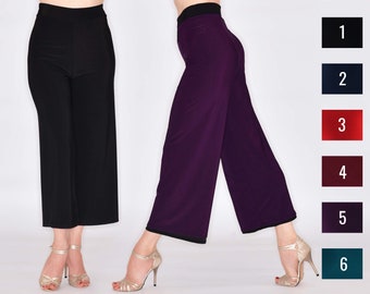 May include: Two pairs of wide-leg pants, one black and one purple, are shown on two mannequins. The mannequins are wearing gold heels.