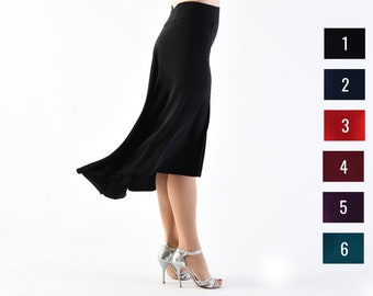 May include: A black skirt with a flowing design, worn by a person with silver heels. The skirt is knee-length and has a high waist.