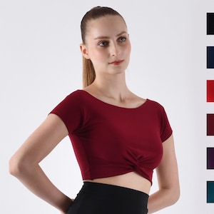 May include: A maroon crop top with short sleeves and a twist detail at the front.