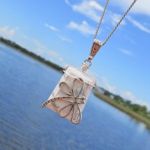 May include: A silver necklace with a white howlite stone pendant featuring a silver dragonfly design.