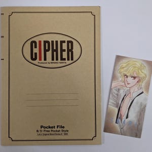 May include: A tan pocket file with the word "CIPHER" in a brown oval, and a color illustration of a manga character with blonde hair. The file also has the text "Produced by MINAKO NARITA" and "Pocket File".