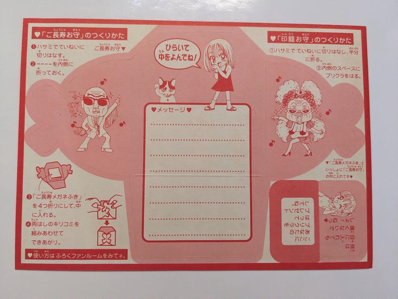 May include: A folded pink paper with Japanese text and illustrations. The paper features cartoon characters, instructions, and a space for a message. The design includes hearts, musical notes, and a cat.