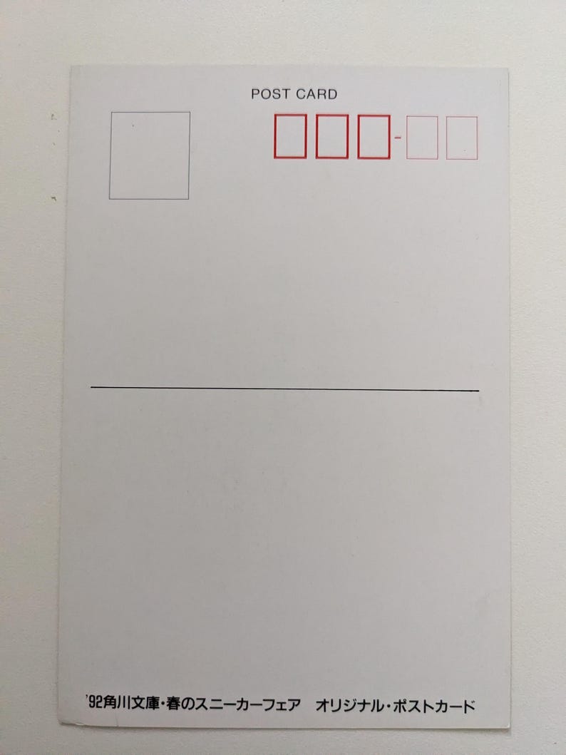 Pu&ograve; includere: Una cartolina bianca con le parole "POST CARD" stampate in alto. Ha una scatola rettangolare nell'angolo in alto a sinistra e caselle rosse per i francobolli. Testo giapponese stampato in basso.