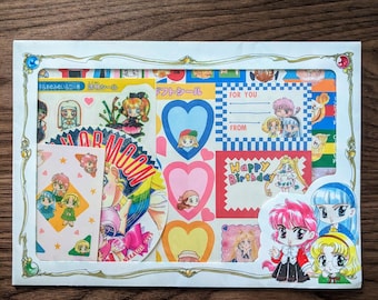 Puede incluir: Una colección de pegatinas coloridas con ilustraciones de estilo anime. Las pegatinas incluyen corazones, personajes y texto como "Happy Birthday" y "For You". Las pegatinas están dispuestas en un marco blanco.