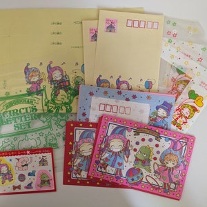 Könnte beinhalten: Ein Set farbenfroher Schreibwaren mit Zirkus-Motiv. Das Set enthält Umschläge, Briefpapier und Aufkleber mit Illustrationen von Clowns, Tieren und anderen Zirkuselementen. Der Text auf der Verpackung lautet "Midorkhan Circus Letter Set".