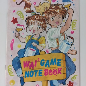 Könnte beinhalten: Ein farbenfrohes Notizbuchcover mit zwei Anime-Charakteren, die Pinsel und Eimer halten. Auf dem Cover steht der Text "Wai² Game Note Book" auf einem Holzschild. Der Hintergrund ist rosa mit Sternen und Konfetti.