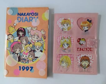 Pode incluir: Dois diários japoneses vintage. O primeiro diário tem uma capa laranja com o texto "NAKAYOSI DIARY" e "1997" com personagens de desenhos animados. O segundo diário é rosa com adesivos de personagens de desenhos animados.