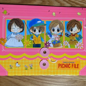 May include: Pink and yellow picnic file folder with cartoon illustrations of children. The folder has a button closure and the text "NAO-CHAN PICNIC FILE". The design includes flowers, a chicken, and musical notes.