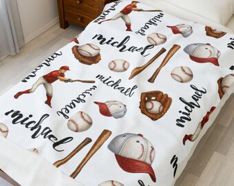 Puede incluir: Manta de franela blanca con temática de béisbol. La manta presenta un patrón repetitivo de pelotas de béisbol, bates, guantes y gorras. El nombre "Michael" está escrito en cursiva negra en toda la manta.
