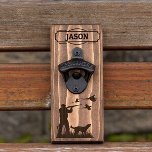 May include: Wooden bottle opener with a black metal opener and a hunting scene with a hunter and dog. The bottle opener is personalized with the name "JASON".