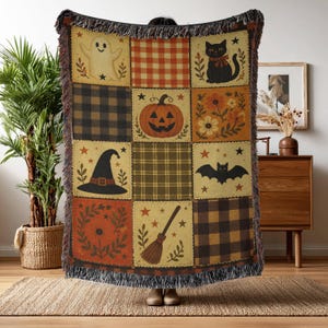 May include: A woven throw blanket featuring a patchwork design with Halloween-themed illustrations including a ghost, a black cat, a jack-o'-lantern, a witch hat, a bat, and a broomstick, interspersed with orange, brown, and black plaid patterns.